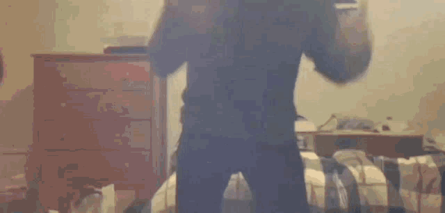 a person is standing on a bed in a bedroom with a dresser in the background
