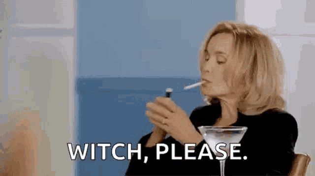 a woman is smoking a cigarette and drinking a martini while sitting at a table .