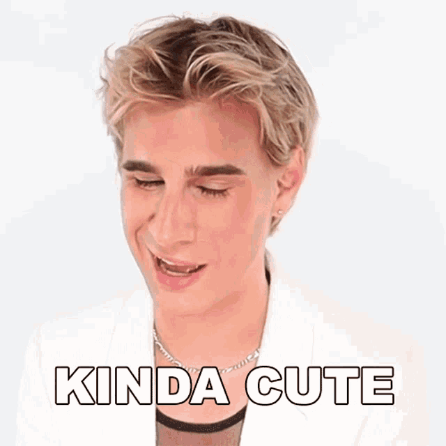 a man wearing a white jacket and a necklace is making a funny face with the words a little bit above him .