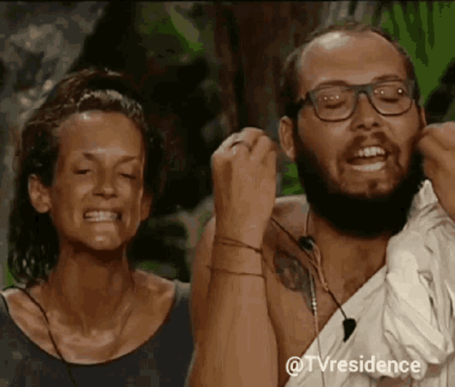 a man with glasses and a beard is standing next to a woman with her eyes closed ..