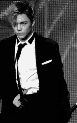 a man in a suit and tie is standing in front of a microphone .