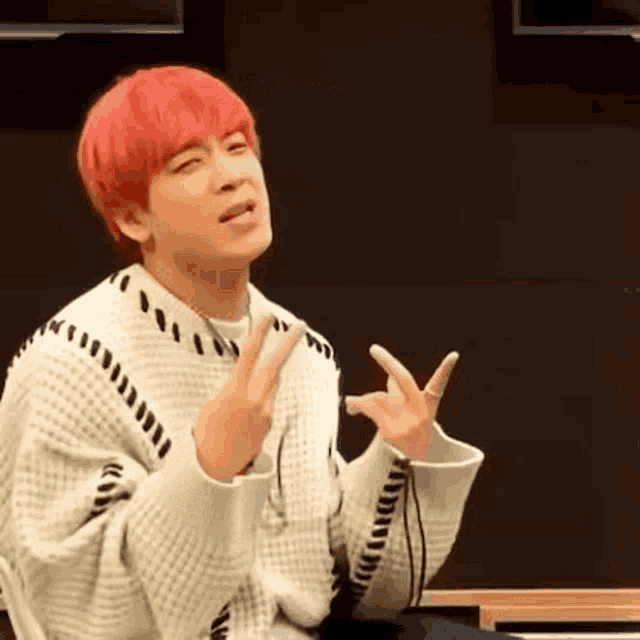 a young man with red hair is making a peace sign with his hands .