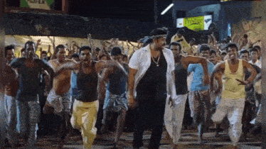 a group of men are dancing in front of a sign that says ' shree krishna ' on it