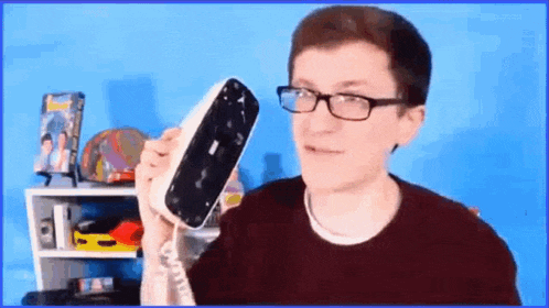 a young man wearing glasses is holding a broken telephone in his hand .