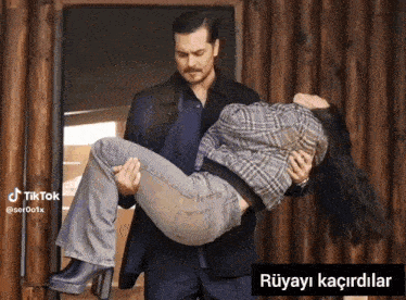 a man is carrying a woman in his arms with a caption that says " rüyayi kacirdilar "