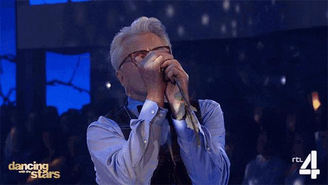 a man singing into a microphone with dancing with the stars written on the bottom