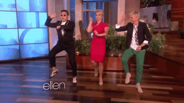 three people are dancing in front of a wall that says ellen on it