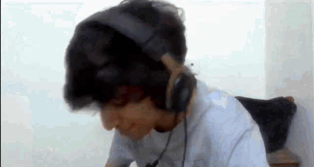 a man wearing headphones and a white shirt is sitting in front of a white wall .