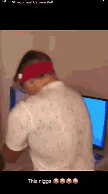 a man wearing a red headband is standing in front of a computer screen with the words this nigga below him