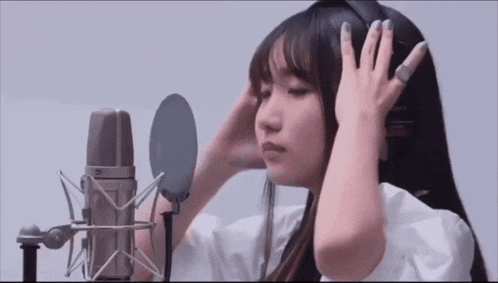 a woman wearing headphones is standing in front of a microphone