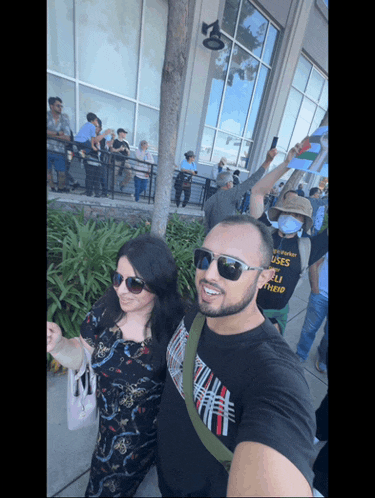 a man wearing sunglasses stands next to a woman wearing a black shirt that says california uses their