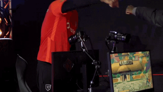 a man in a red shirt is shaking hands with another man in front of a sign that says ' ranked ' on it