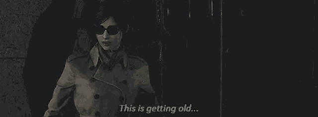 a woman in a trench coat and sunglasses is standing in a dark room and talking .