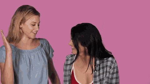 two women are standing next to each other and giving each other a high five .