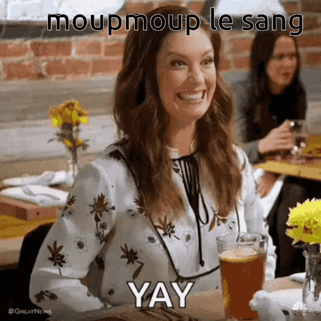 a woman is smiling while sitting at a table with a glass of beer