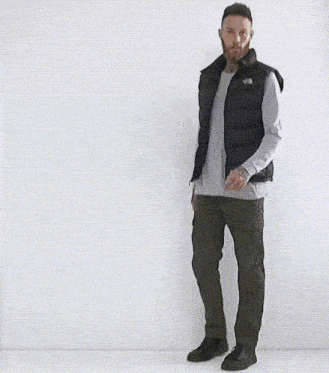 a man with a beard is wearing a black vest and a white shirt
