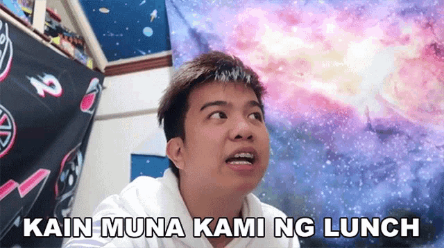 a young man says kain muna kami ng lunch in front of a galaxy
