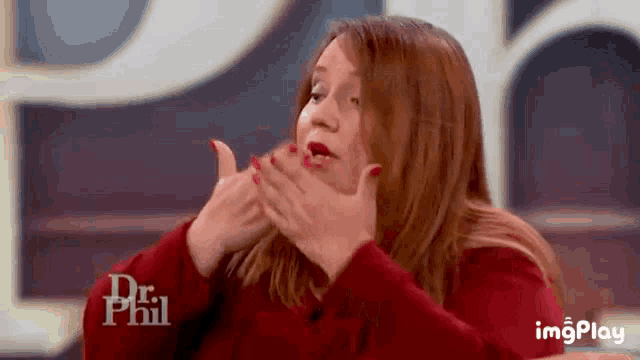 a woman is covering her mouth with her hands while sitting on a dr phil show