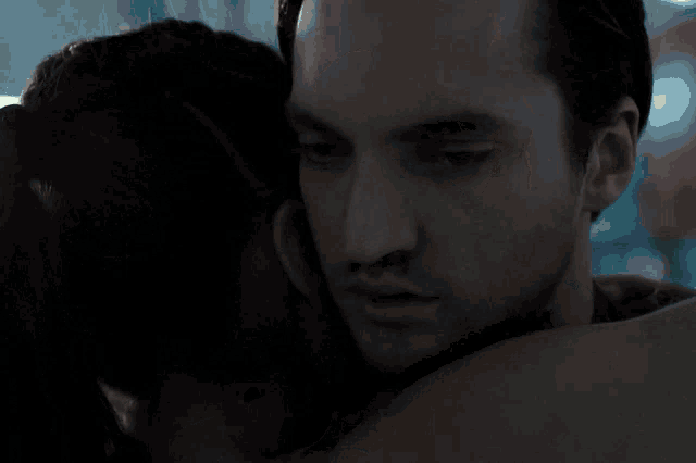 a man and a woman are hugging each other and the woman is crying