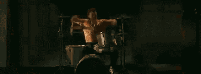 a man is playing drums in front of a drum set on fire