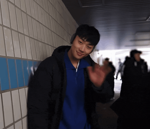 a man wearing headphones and a blue shirt waving his hand