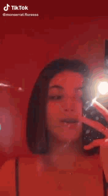 a woman is taking a selfie with her cell phone in front of a mirror .