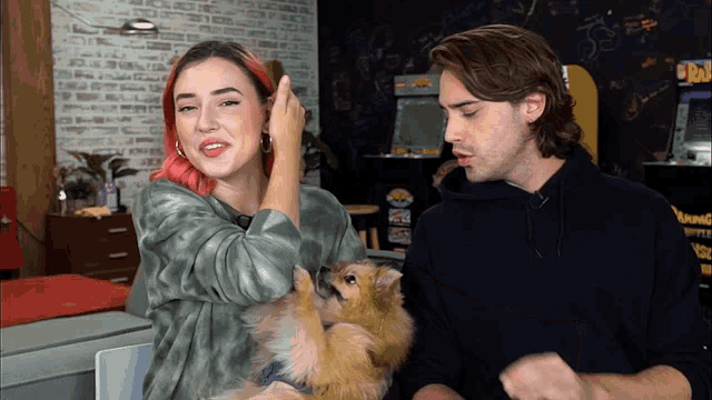 a man and a woman are standing next to a small dog
