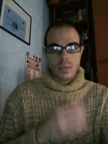 a man wearing glasses and a sweater stands in front of a poster that says monopoly on it