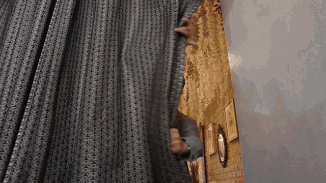 a person peeking out from behind a curtain with a pattern