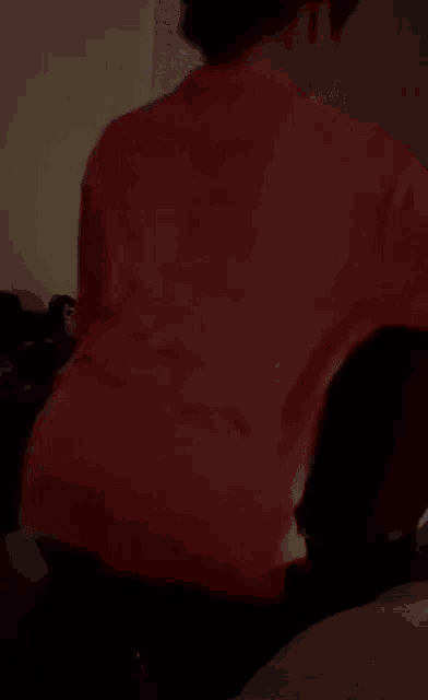 a person wearing a red shirt is sitting on a bed .