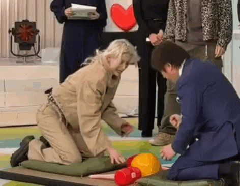 a man in a suit is kneeling down next to a woman in a khaki uniform .