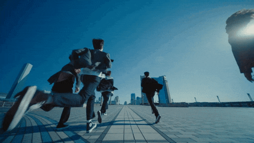 a group of people are running down a brick sidewalk