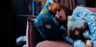 a woman laying on a couch with a blue pillow