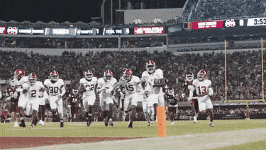 a group of football players are running on a field with the number 30 on their jersey