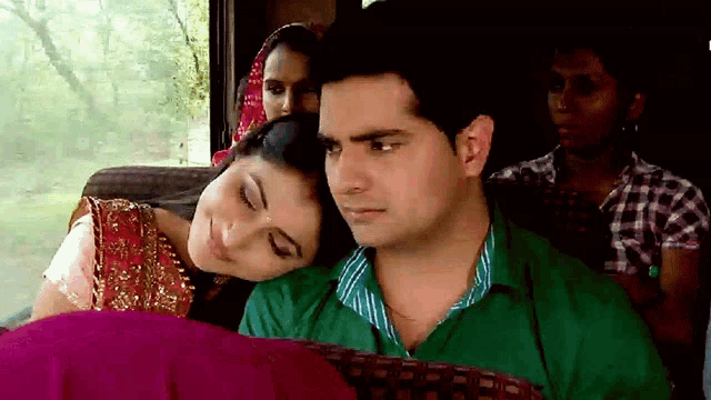 a woman rests her head on a man 's shoulder while sitting on a bus