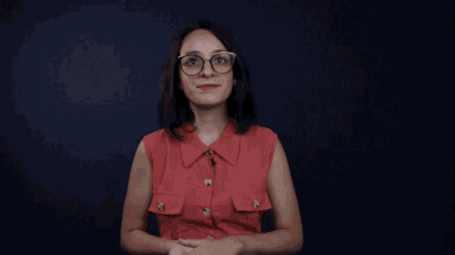 a woman with glasses and a tattoo on her arm raises her fist