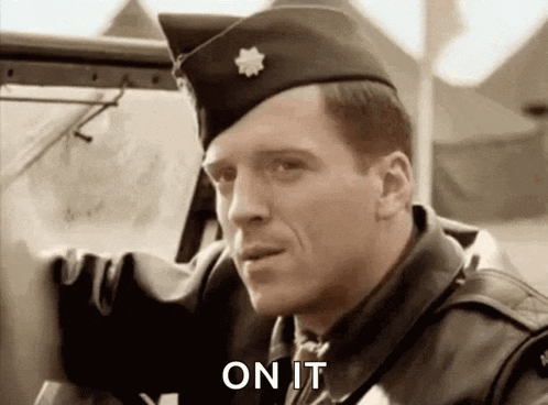 a man in a military uniform is standing next to a car and saying on it .