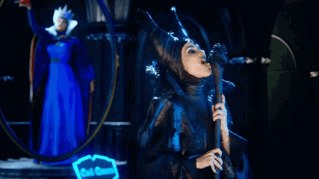 a woman in a maleficent costume is holding a cane