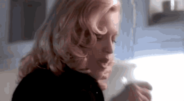 a close up of a woman 's face with blonde hair and a black shirt