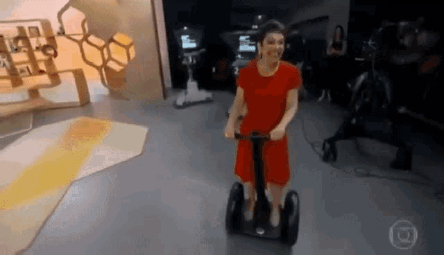 a woman in a red dress is riding a segway on a stage .