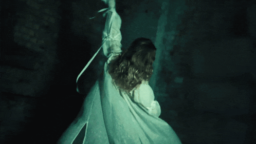 a woman in a white shirt is laying on her back with her arms outstretched