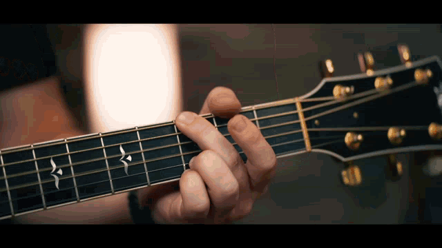 a close up of a person playing an acoustic guitar with a star on the neck