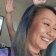 a woman with blue hair and a donut on her head is smiling .