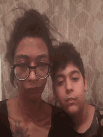 a woman wearing glasses is laying next to a boy wearing glasses