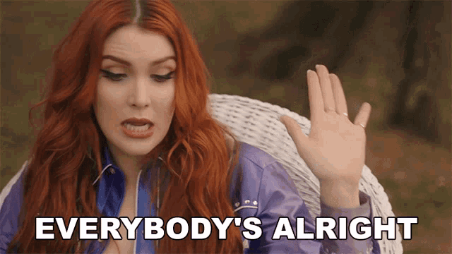 a woman with red hair says " everybody 's alright " with her hand up