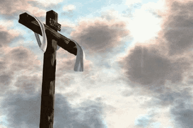 a wooden cross with the word jesus on it against a cloudy sky