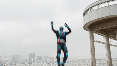 a man in a blue and black superhero costume jumps in the air