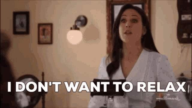 a woman is sitting in a room holding a book and saying `` i don 't want to relax ''