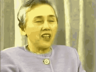 a woman in a purple sweater is making a funny face with her eyes closed .