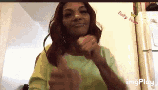 a woman is giving a thumbs up in front of a refrigerator .